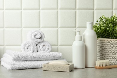 Different bath accessories and personal care products on gray table near white tiled wall