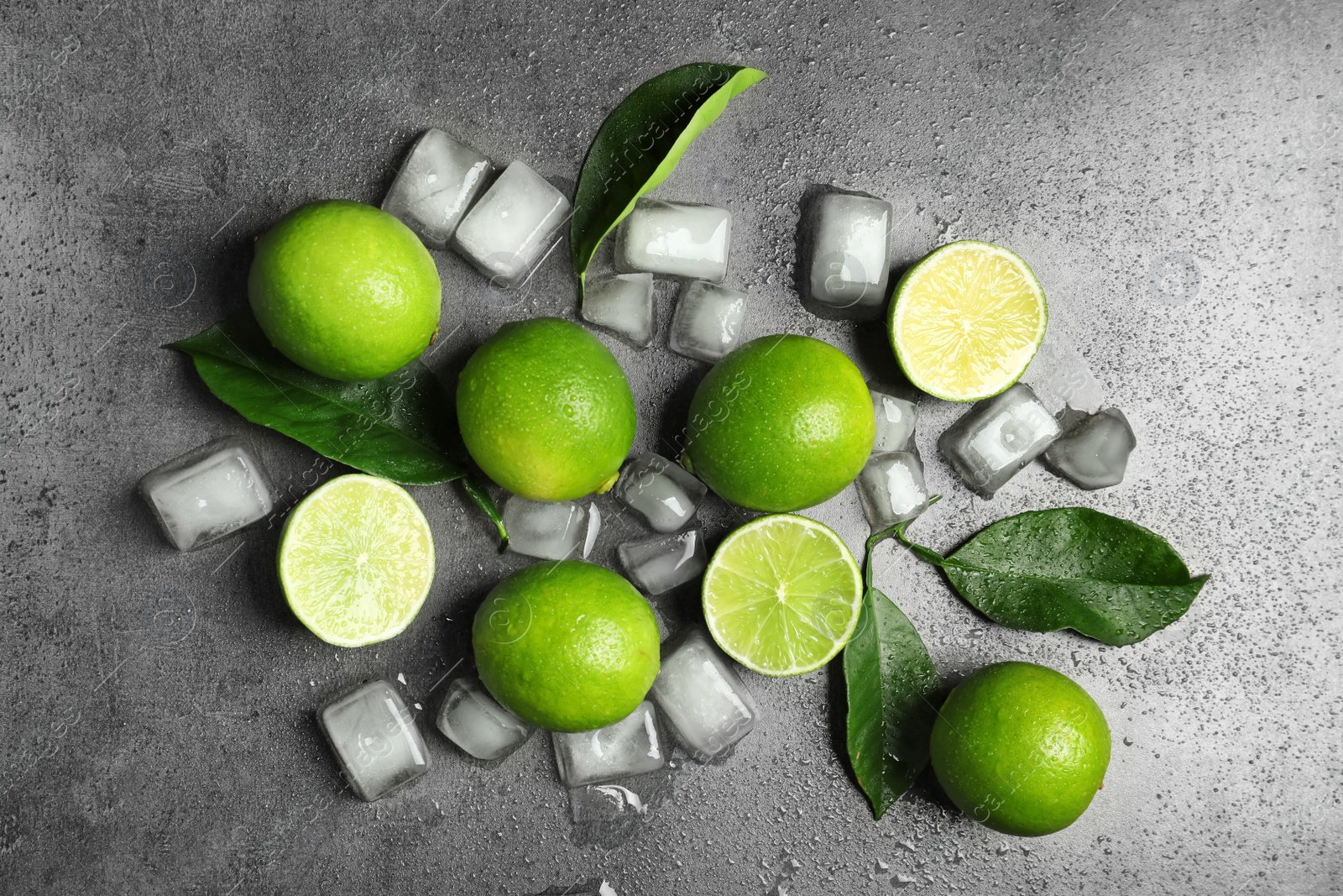 Photo of Composition with fresh ripe limes and ice cubes on gray background, top view