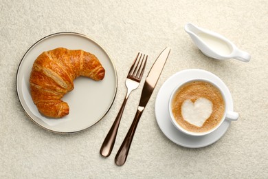 Photo of Delicious fresh croissant served with coffee on beige table, flat lay