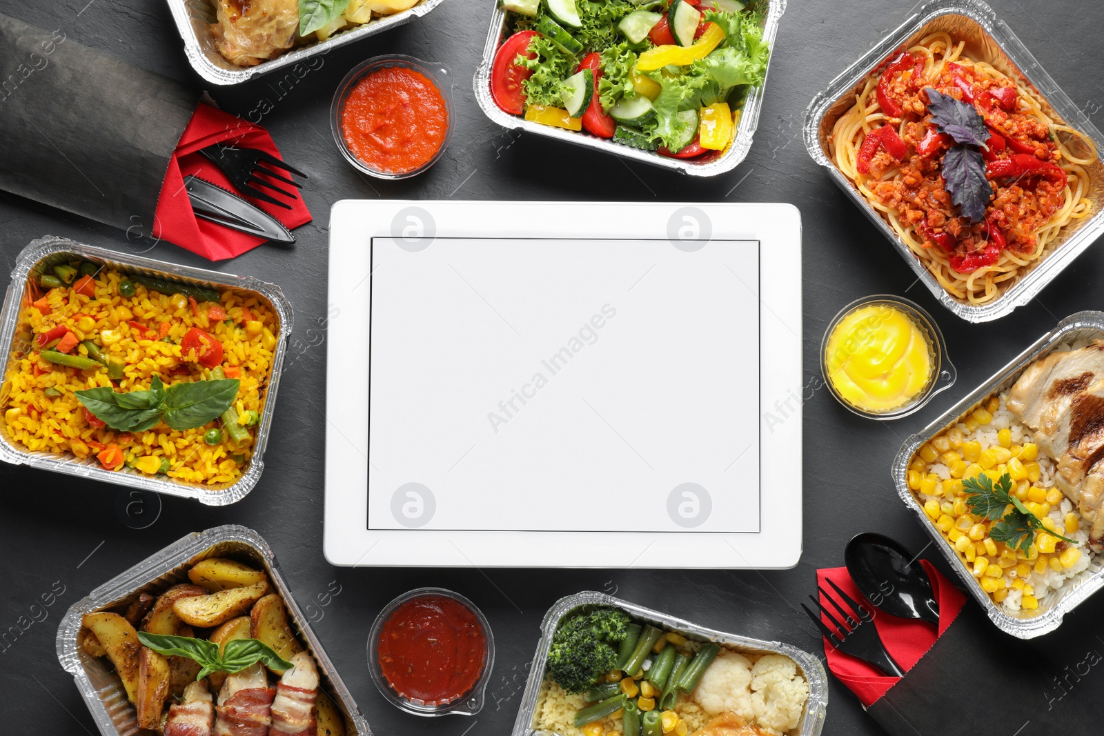 Photo of Flat lay composition with lunchboxes and tablet on grey table, mockup for design. Healthy food delivery