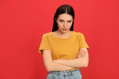 Angry young woman on red background. Hate concept