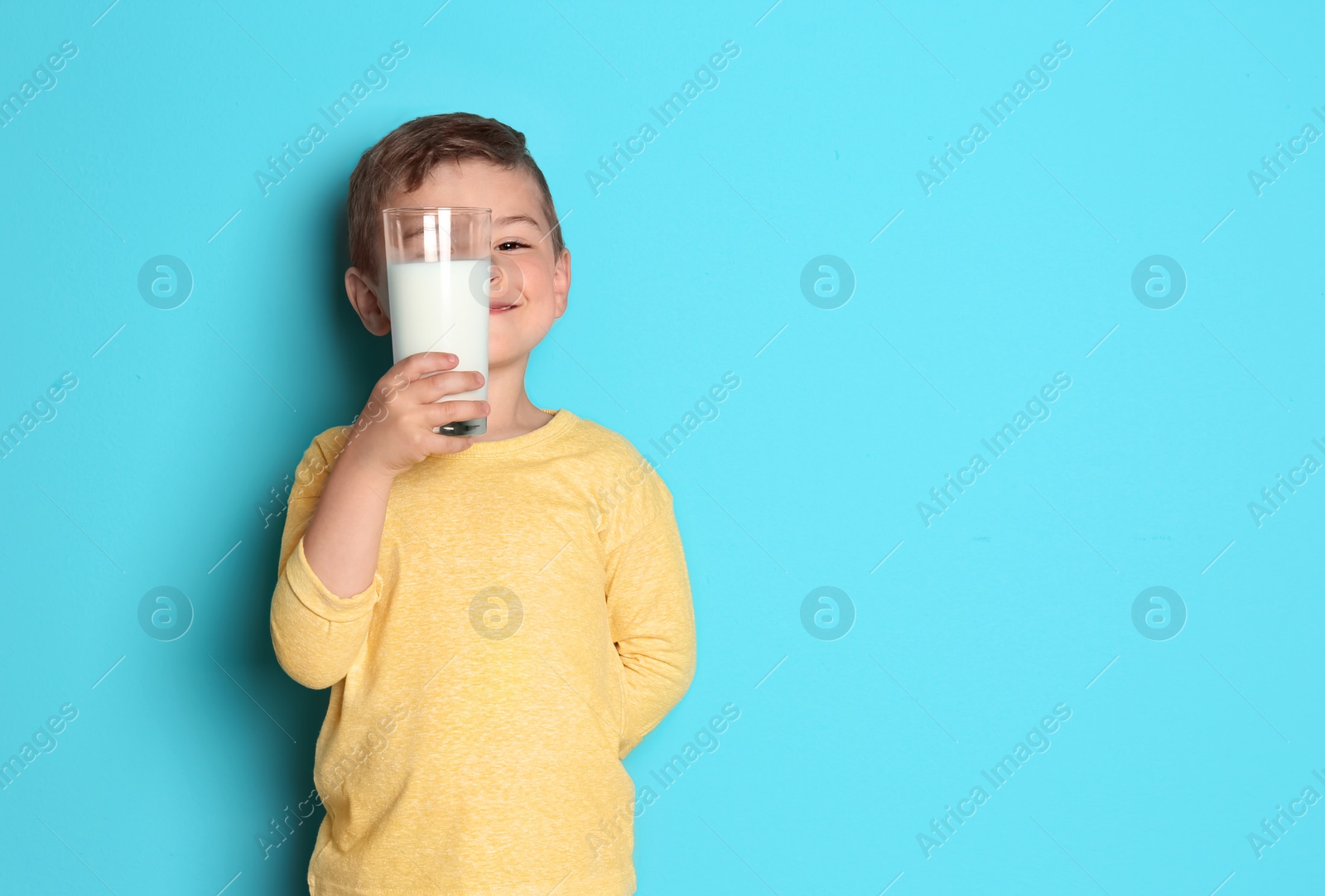 Photo of Cute little boy with glass of milk on color background