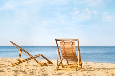 Photo of Sandy beach with empty wooden sunbeds on sunny day