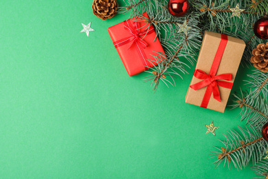 Photo of Flat lay composition with decorated fir branches and gifts on green background, space for text. Winter holidays