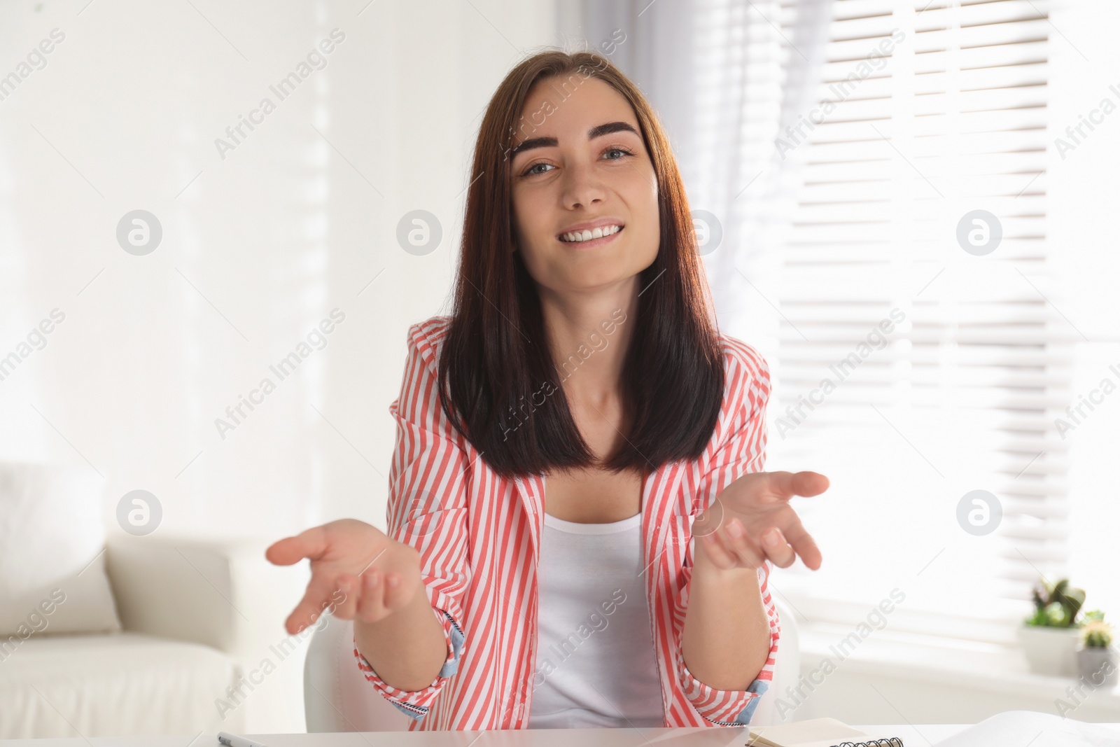 Photo of Young woman talking to her coworkers through video conference indoors, view from webcam