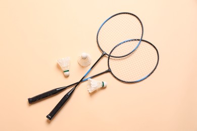 Feather badminton shuttlecocks and rackets on beige background, flat lay