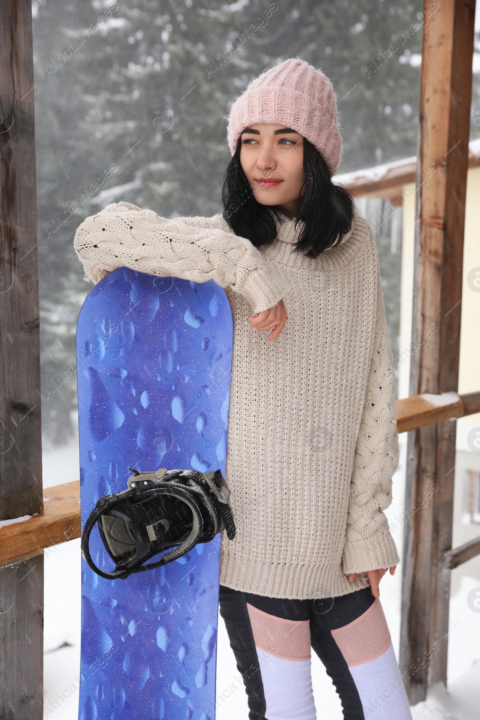 Photo of Young woman with snowboard wearing winter sport clothes outdoors