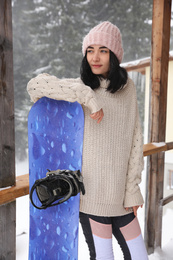 Photo of Young woman with snowboard wearing winter sport clothes outdoors