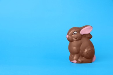 Photo of Chocolate bunny on light blue background, space for text. Easter celebration