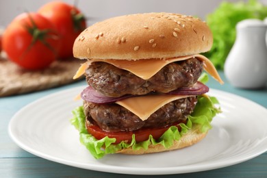 Tasty hamburger with patties, cheese and vegetables on table, closeup