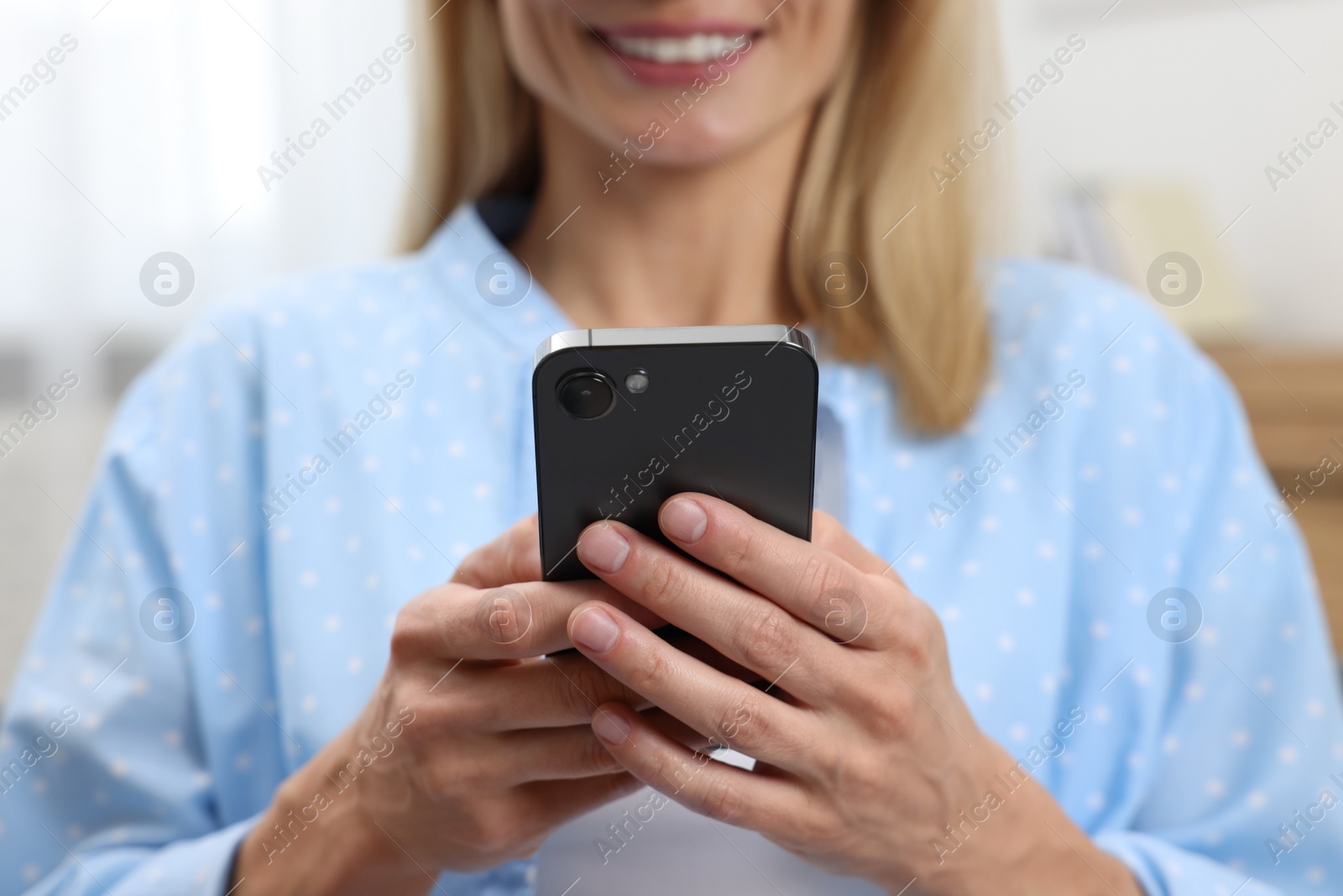 Photo of Happy woman sending message via smartphone at home, closeup