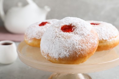 Delicious donuts with jelly and powdered sugar on pastry stand, closeup
