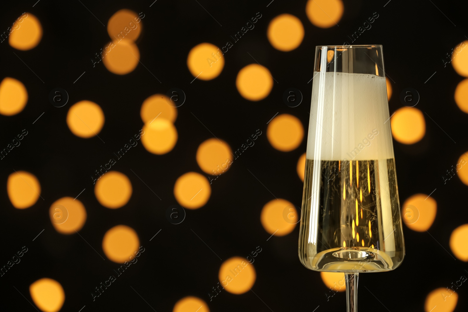 Photo of Glass of champagne against blurred lights. Space for text