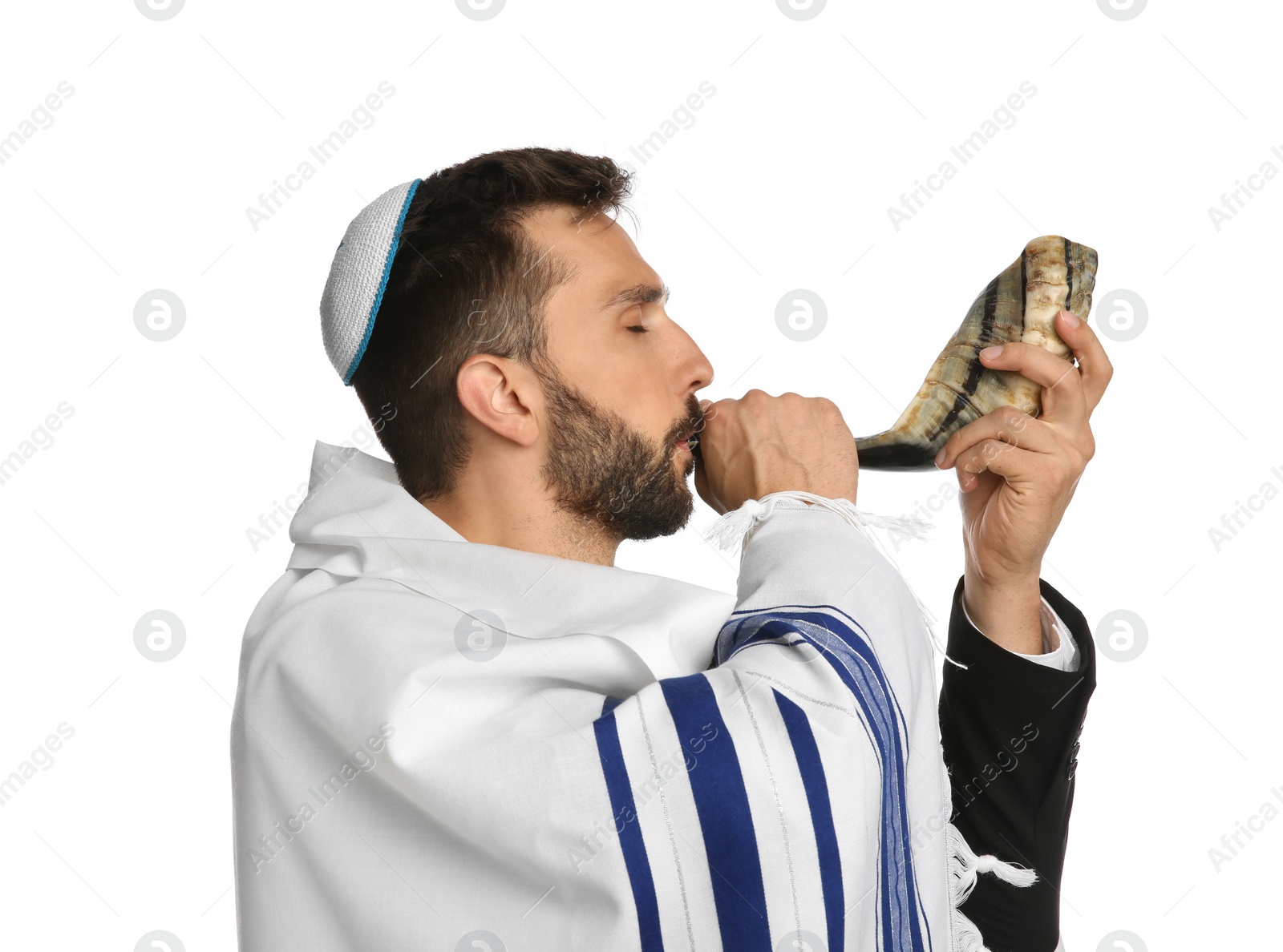 Photo of Jewish man with kippah and tallit blowing shofar on white background. Rosh Hashanah celebration