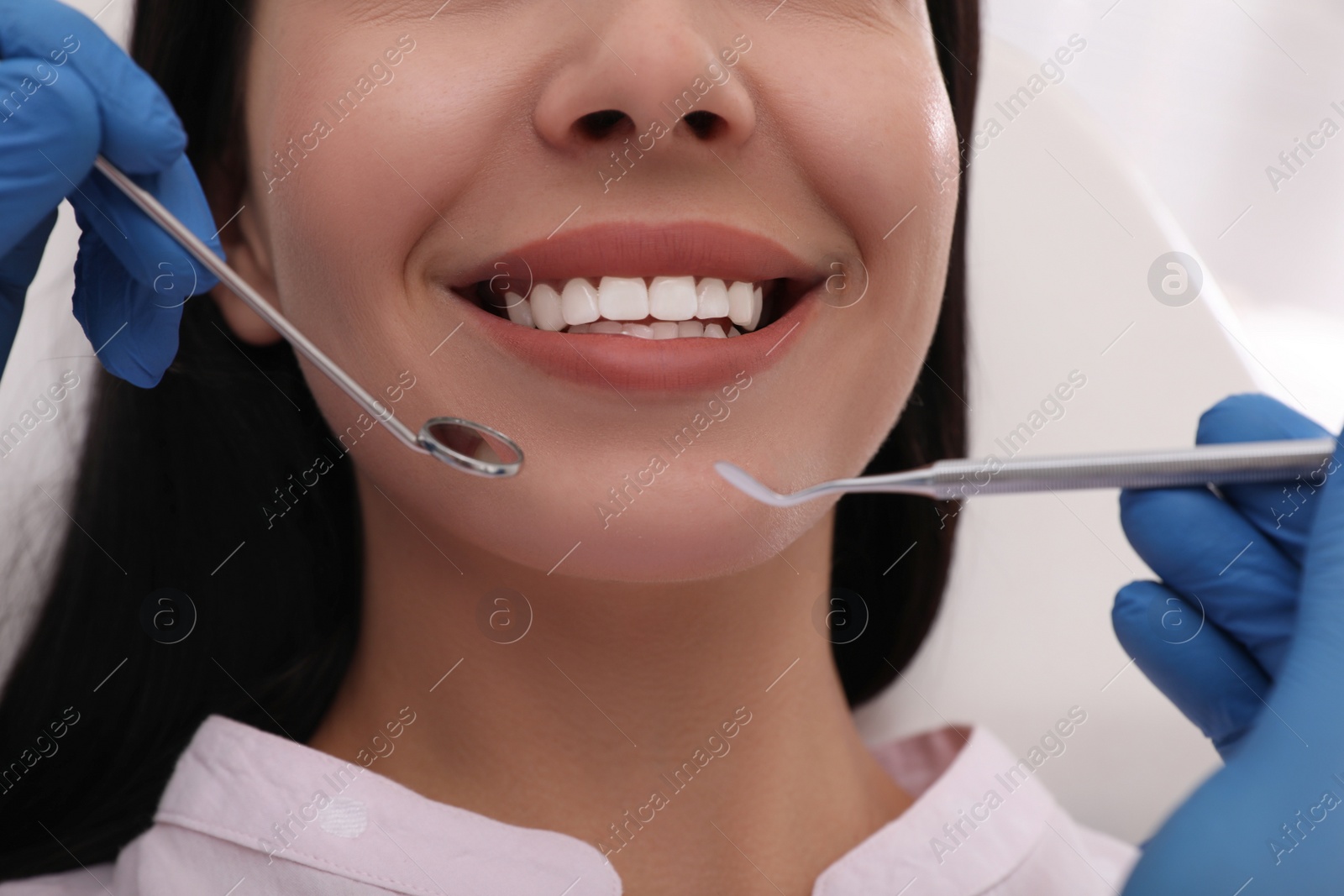 Photo of Dentist examining young woman's teeth, closeup view