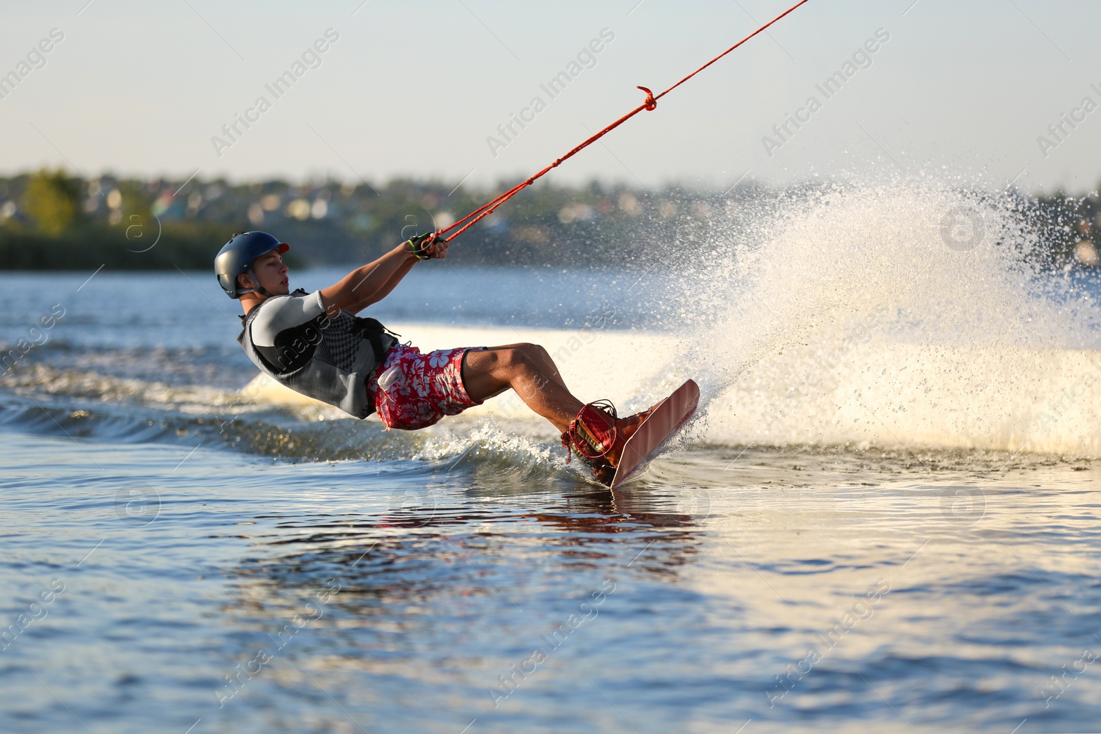 Photo of Teenage boy wakeboarding on river. Extreme water sport