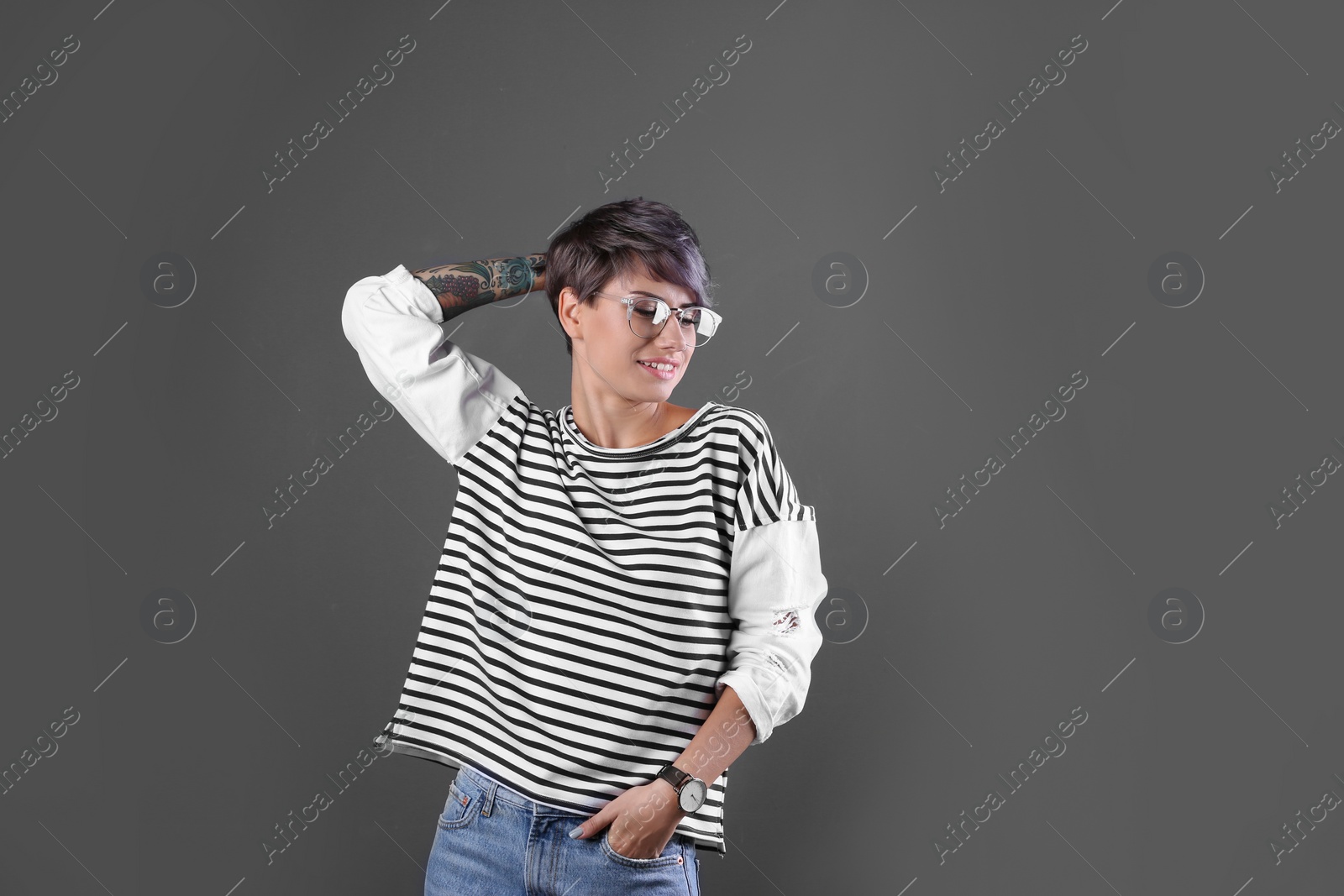 Photo of Trendy young woman with tattoo in glasses on color background