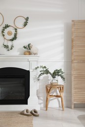 Stylish room with beautiful fireplace and eucalyptus branches