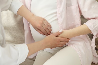 Doula taking care of pregnant woman at home, closeup. Preparation for child birth