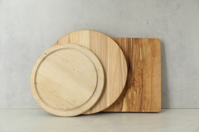 Photo of Different cutting boards on white table near light wall