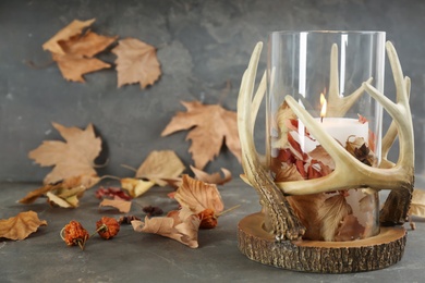 Photo of Stylish holder with burning candle and autumn decor on grey stone table. Space for text