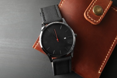 Photo of Stylish wrist watch and wallet on dark background. Fashion accessory