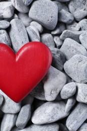 Photo of Red decorative heart on grey stones, top view