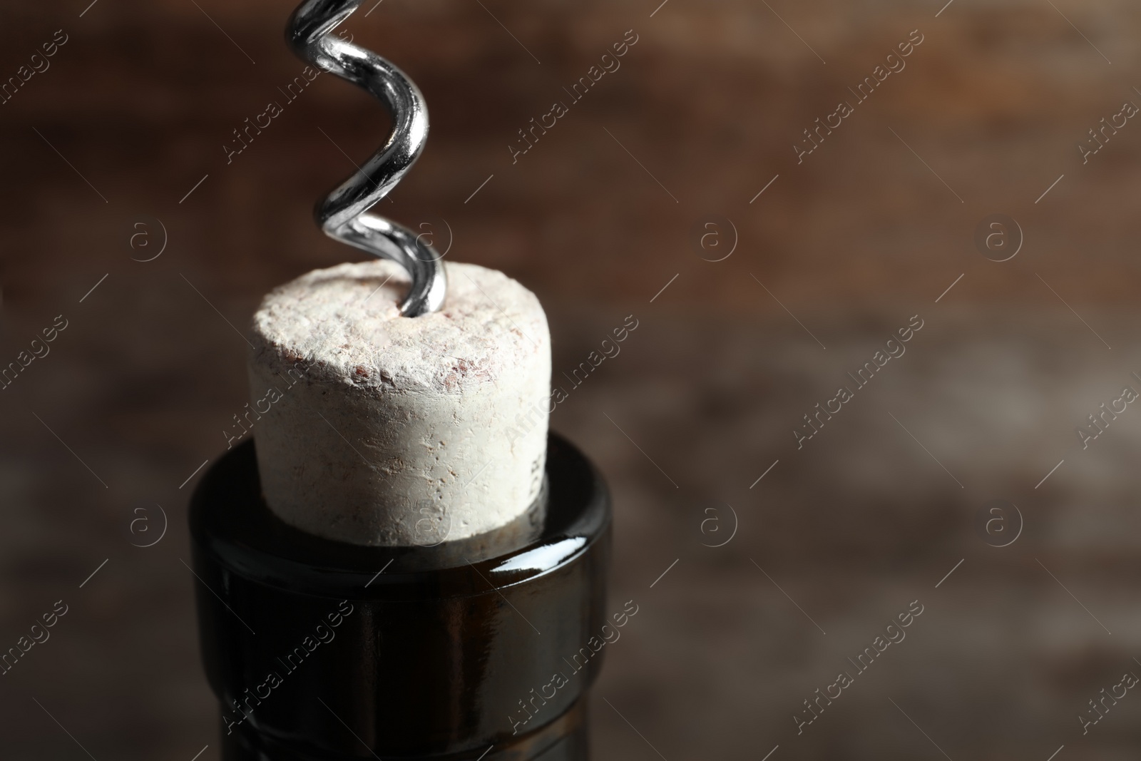 Photo of Opening bottle of wine with corkscrew on blurred background, closeup