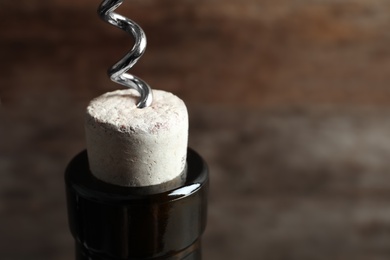 Photo of Opening bottle of wine with corkscrew on blurred background, closeup