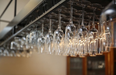 Many clean glasses on metal rack in restaurant