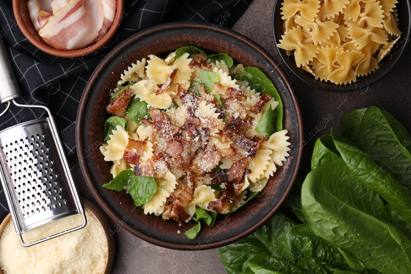 Photo of Tasty pasta with bacon and basil on brown table, flat lay