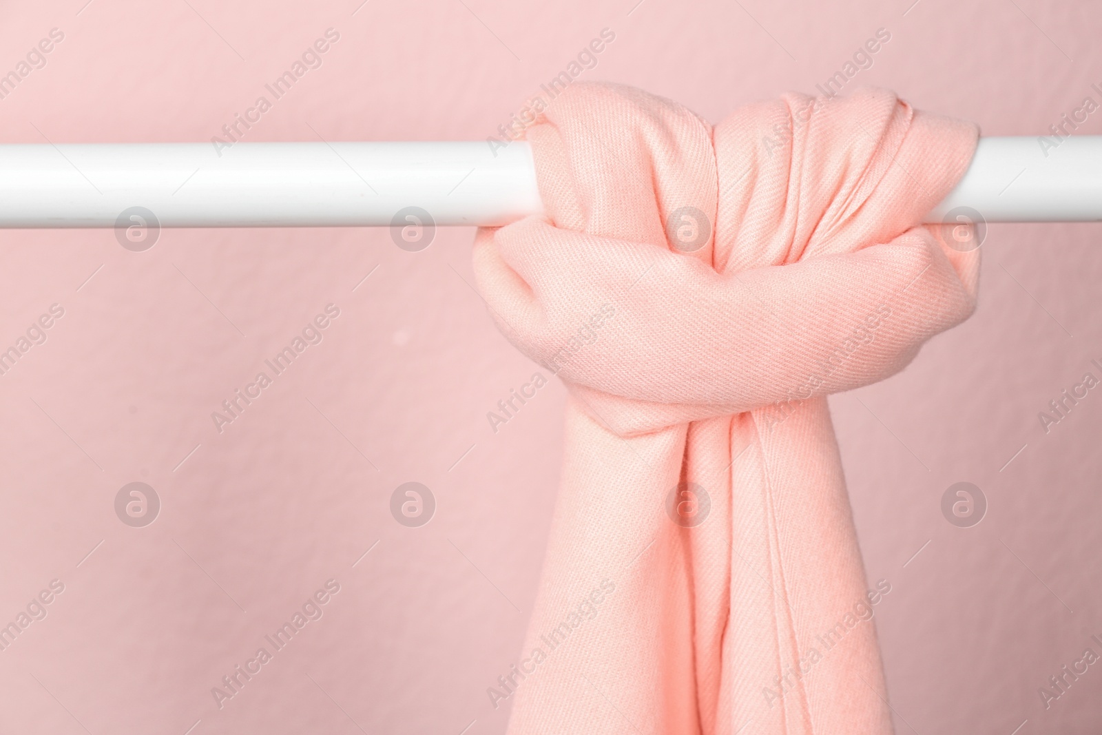 Photo of Elegant scarf on wardrobe rack against pink background, space for text. Autumn clothes