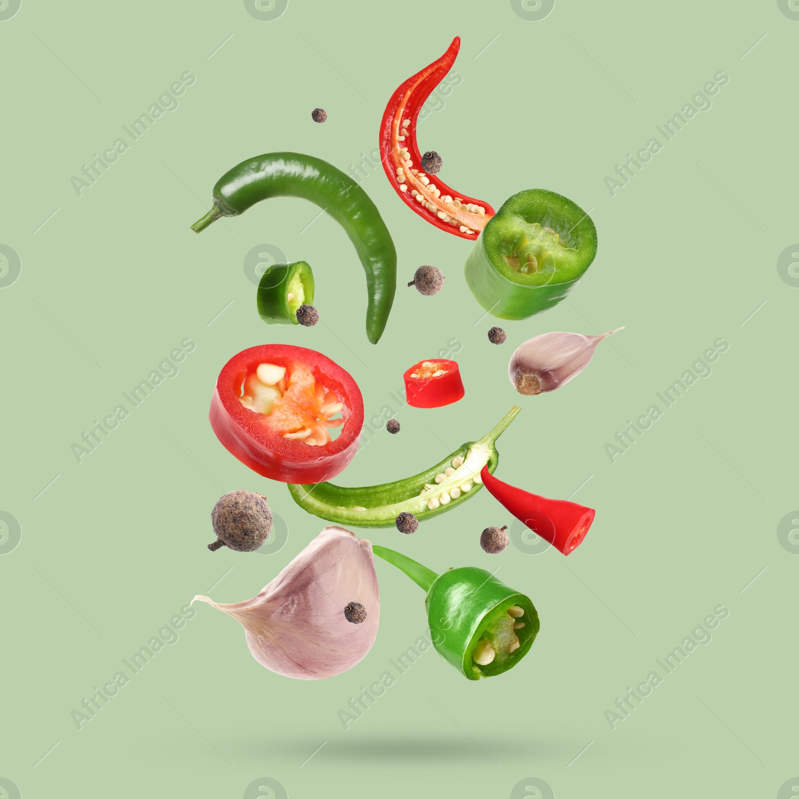 Image of Different spices falling on light green background