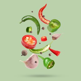 Different spices falling on light green background