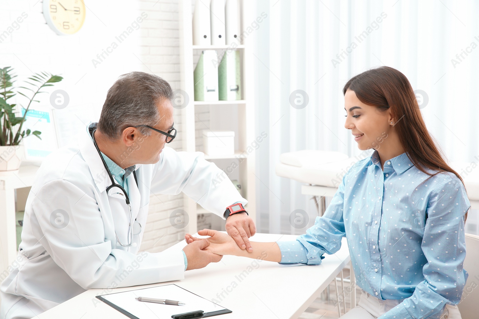 Photo of Doctor checking young woman's pulse with fingers in hospital