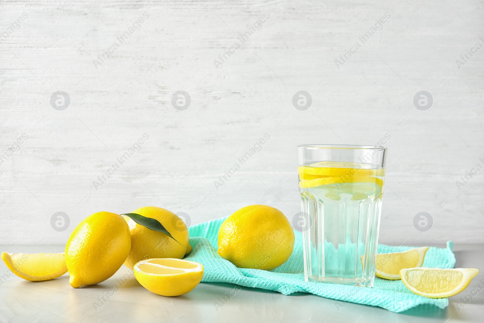 Photo of Glass with lemon water and fresh fruits on table