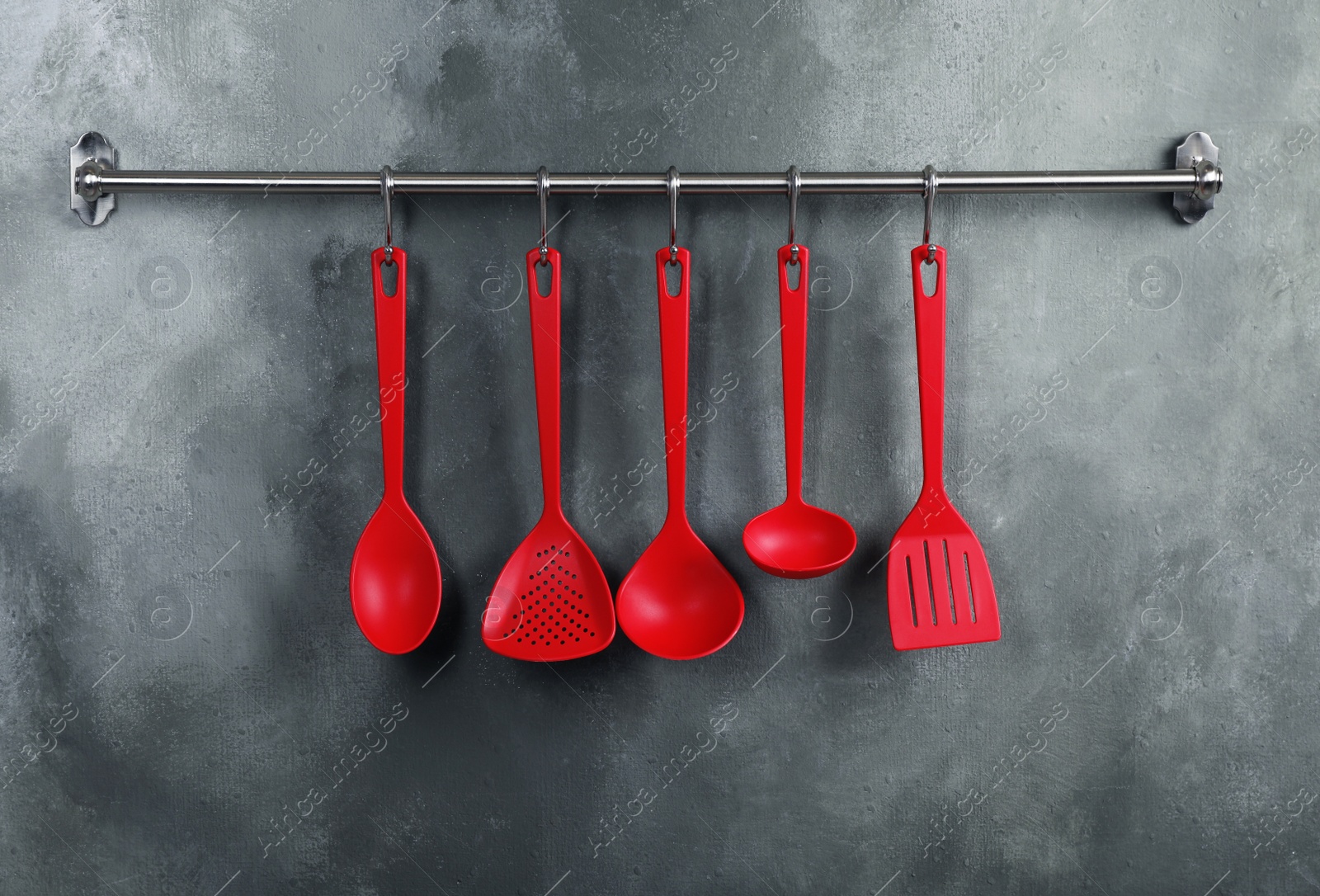 Photo of Rack with clean kitchen utensils on color wall