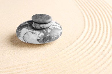 Photo of Zen garden stones on beige sand with pattern. Space for text