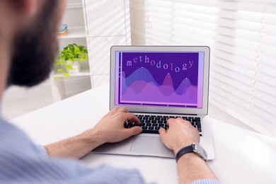 Image of Methodology concept. Man using modern laptop at white table indoors, closeup