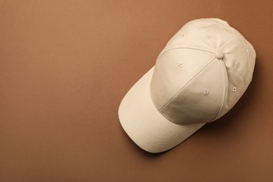 Photo of Baseball cap on brown background, top view. Space for text