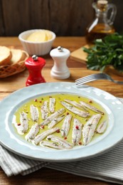 Photo of Tasty pickled anchovies with spices on wooden table