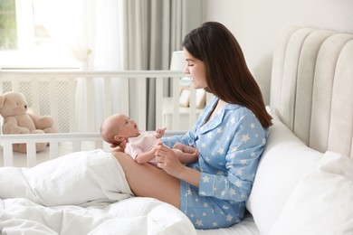 Photo of Young mother with her cute newborn baby in bed at home