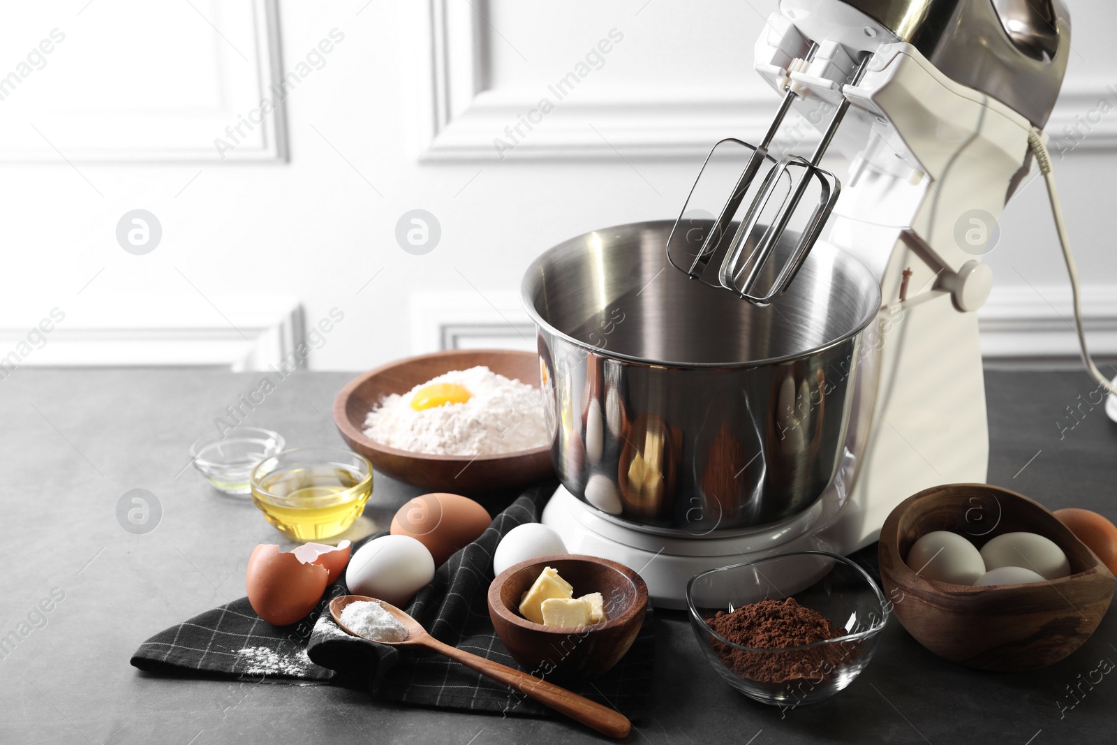 Photo of Stand mixer and different ingredients for dough on grey table