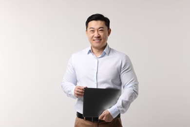 Portrait of happy man with laptop on light background