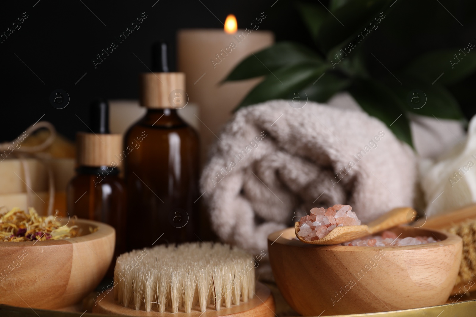 Photo of Spa composition. Pink sea salt, brush and bottles on black background, closeup