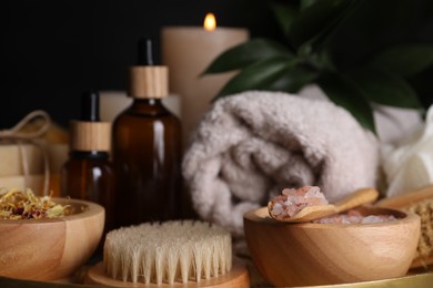 Spa composition. Pink sea salt, brush and bottles on black background, closeup