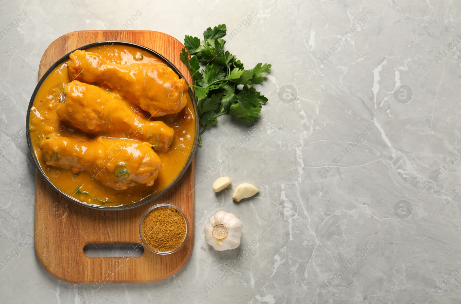 Photo of Tasty chicken curry and ingredients on grey textured table, flat lay. Space for text