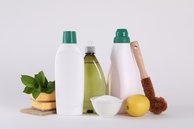 Photo of Bottles of cleaning product, brush, sponges and lemon isolated on white