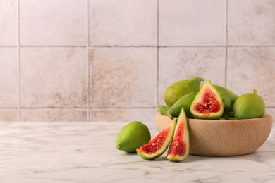 Cut and whole green figs on white marble table, space for text