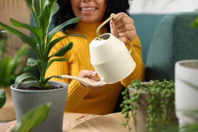 Closeup of happy woman watering beautiful potted houseplants at home